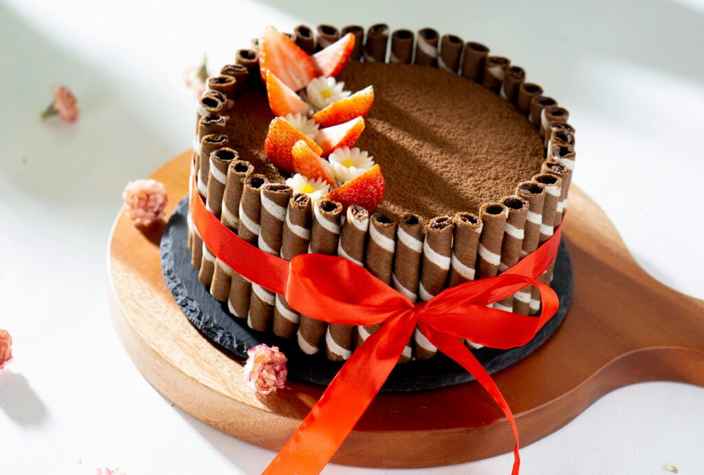 Delicious chocolate cake adorned with strawberries and a red ribbon, perfect for celebrations.