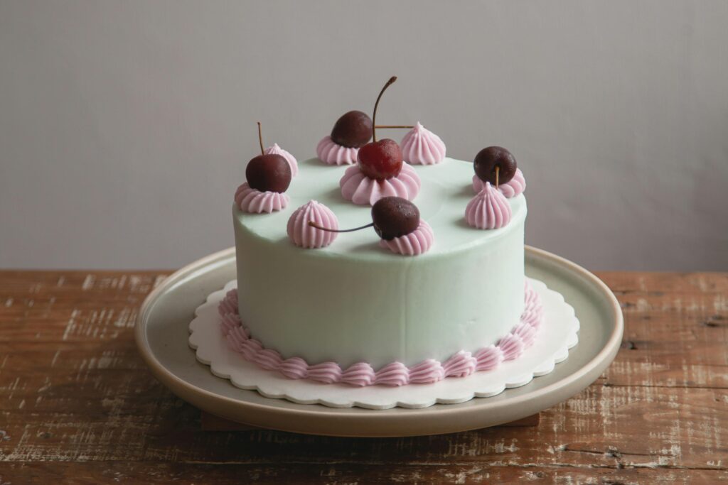 A beautifully decorated layer cake with cherries and pastel frosting, perfect for dessert.